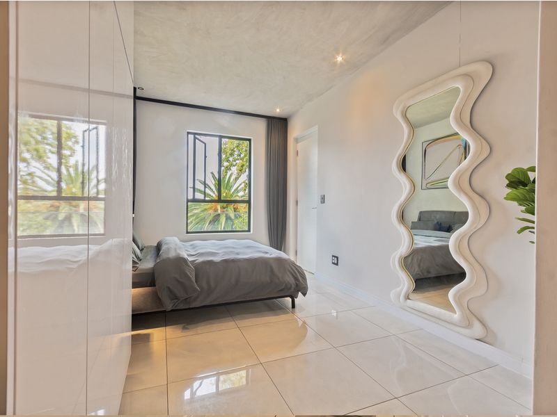Modern bedroom featuring high-gloss built-in cupboards, polished tile flooring, and recessed lighting, offering a clean and contemporary living space.
