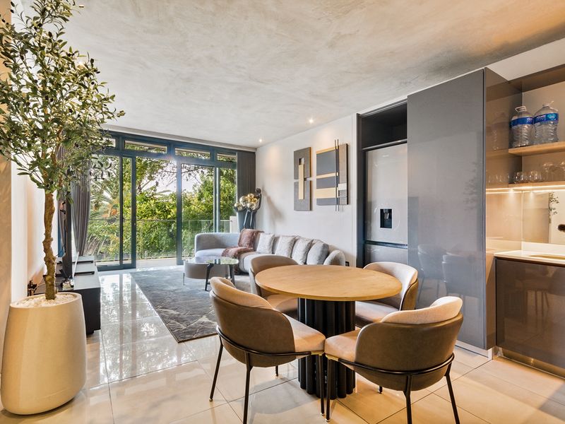 Modern open-plan living and dining area featuring sleek built-in cabinetry, high-gloss tiled floors, and large sliding doors leading to a balcony.
