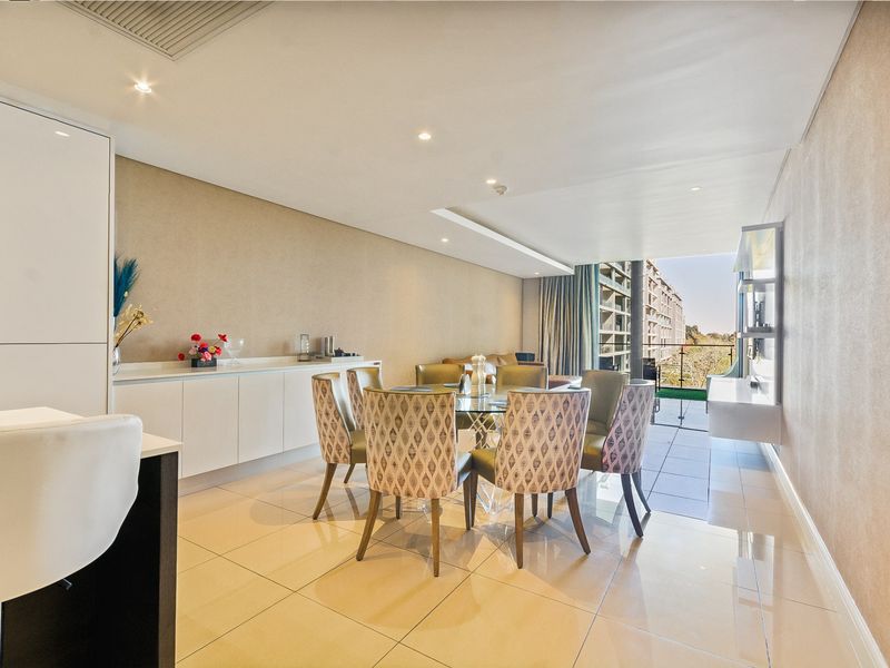 Modern open-plan living and dining area featuring sleek tiled floors, recessed lighting, and seamless access to a private balcony.
