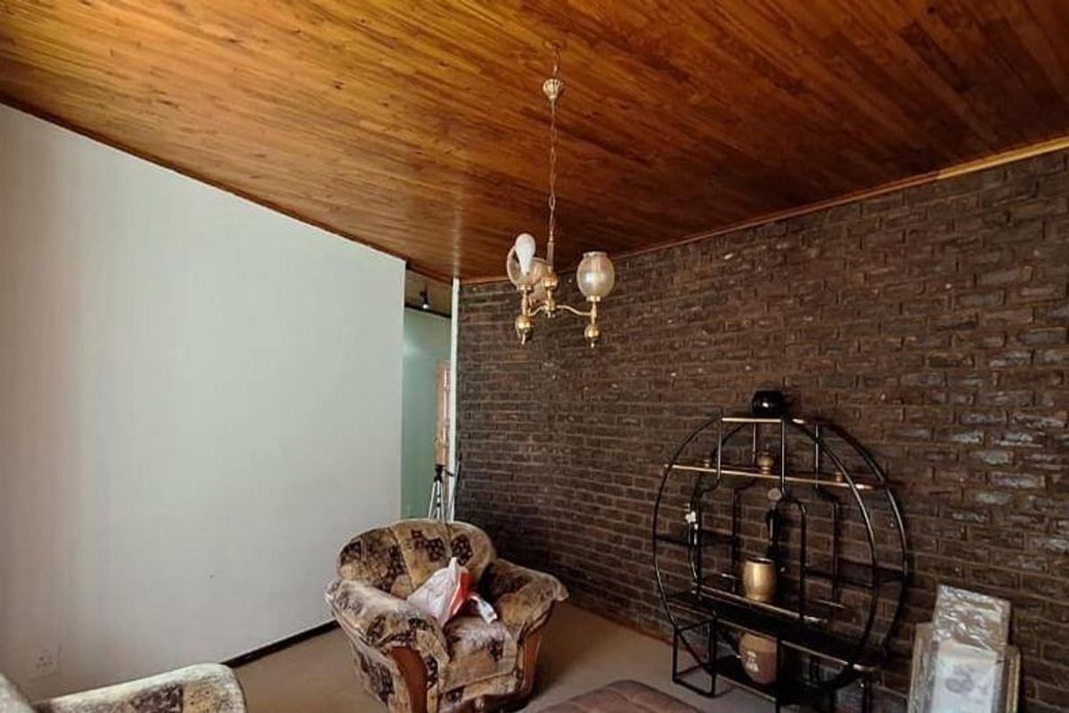 Living room featuring a rustic exposed brick wall and a warm timber-paneled ceiling, creating a cozy and traditional atmosphere.