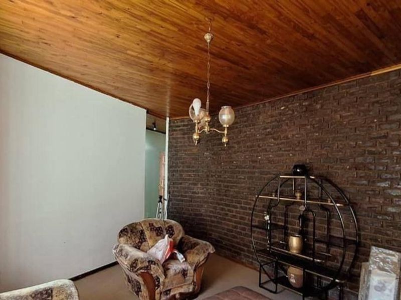 Living room featuring a rustic exposed brick wall and a warm timber-paneled ceiling, creating a cozy and traditional atmosphere.