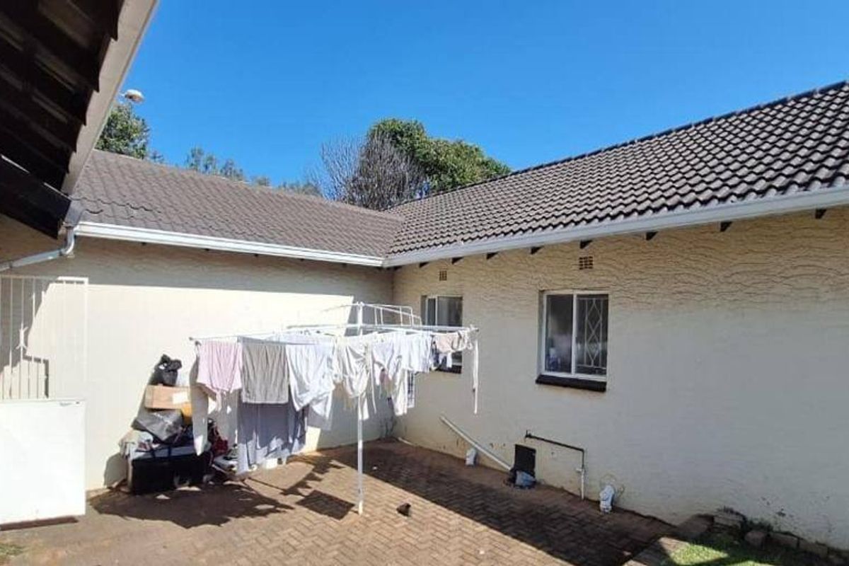 Rear courtyard area featuring paved flooring, tiled roof, and exterior wall access with security bars on windows.