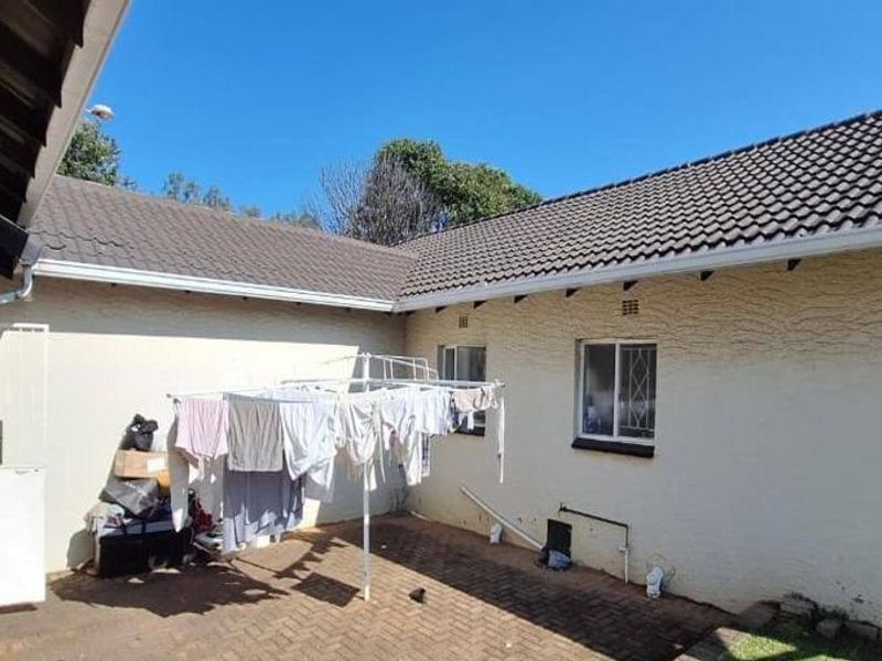 Rear courtyard area featuring paved flooring, tiled roof, and exterior wall access with security bars on windows.