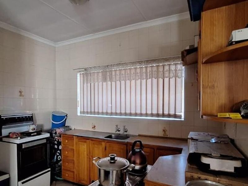A functional kitchen featuring wooden cabinetry, tiled wall finishes, and a freestanding stove, offering potential for modernization and cosmetic updates.