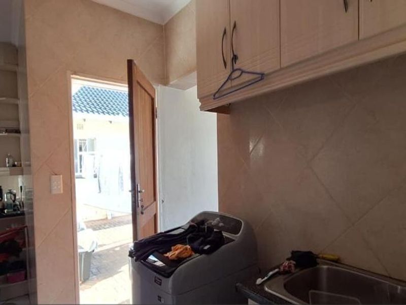 A functional laundry area featuring built-in cabinetry, a stainless steel sink, and direct access to the exterior rear of the property.