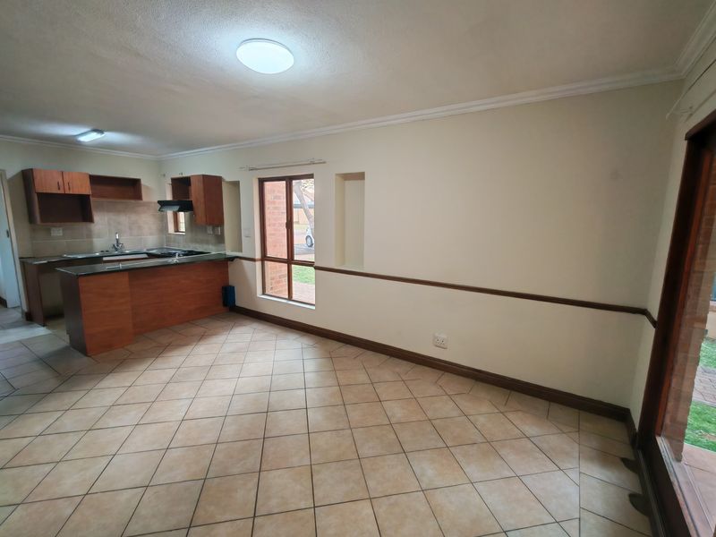 Open plan living and kitchen area featuring tiled flooring, built-in cabinetry with granite countertops, and a recessed wall niche in a neutral setting.