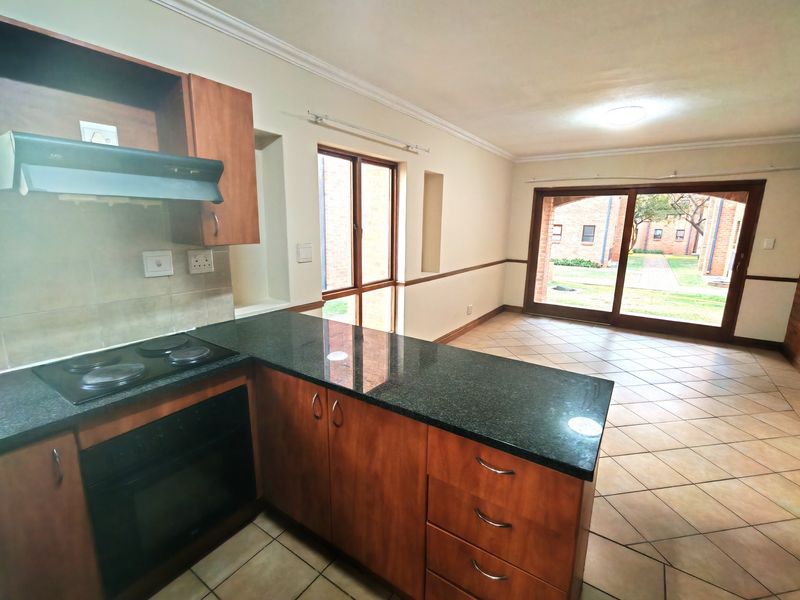 Open-plan kitchen and living area featuring wooden cabinetry, granite countertops, tiled floors, and large sliding doors leading to the exterior.