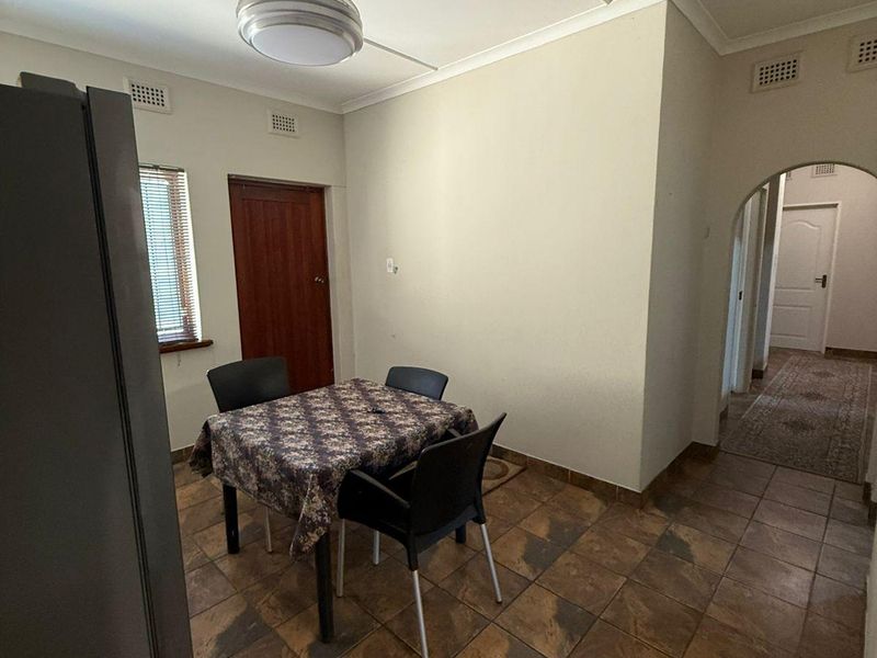 Dining area featuring tiled flooring, a ceiling fan, and an arched entryway leading to the hallway.