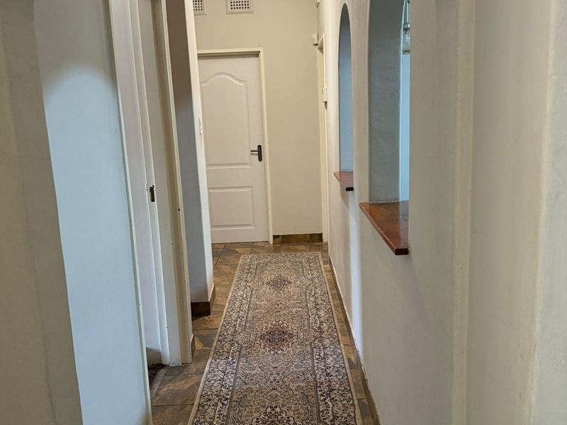 A bright hallway featuring arched wall openings, tiled flooring, and coved ceilings, providing access to multiple rooms within the townhouse.