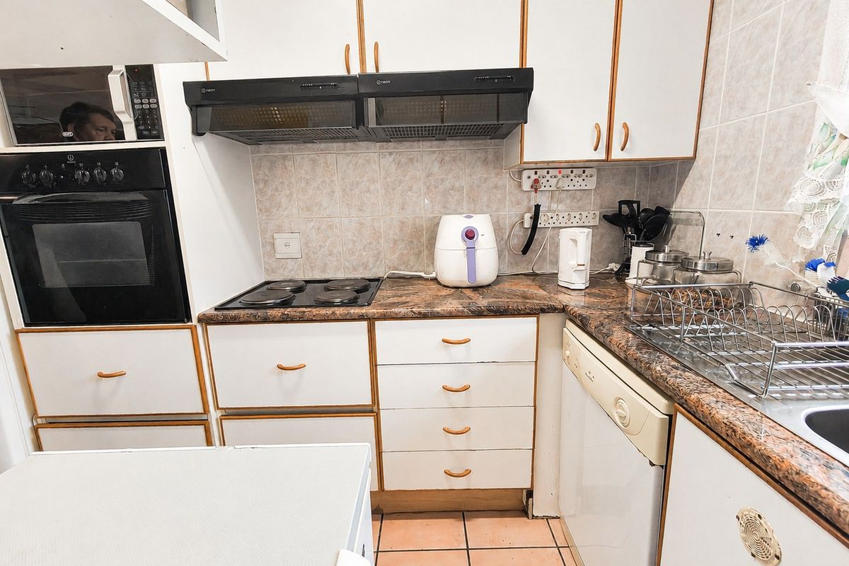 A functional kitchen featuring built-in cabinetry, an integrated oven and hob, tiled backsplash, and durable laminate countertops.