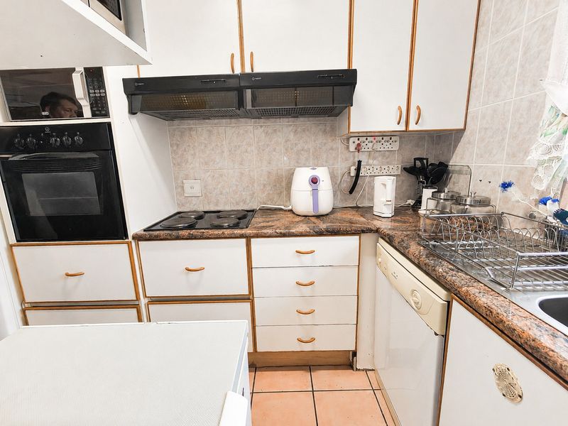A functional kitchen featuring built-in cabinetry, an integrated oven and hob, tiled backsplash, and durable laminate countertops.
