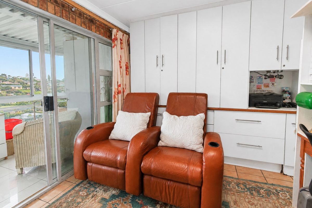 Living area featuring built-in white cabinetry, tiled flooring, and a sliding glass door providing access to an outdoor balcony.