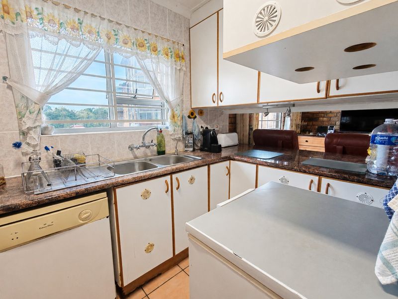 A functional kitchen featuring laminate countertops, double basin sink, tiled backsplash, and ample built-in cabinetry with an integrated extractor fan.