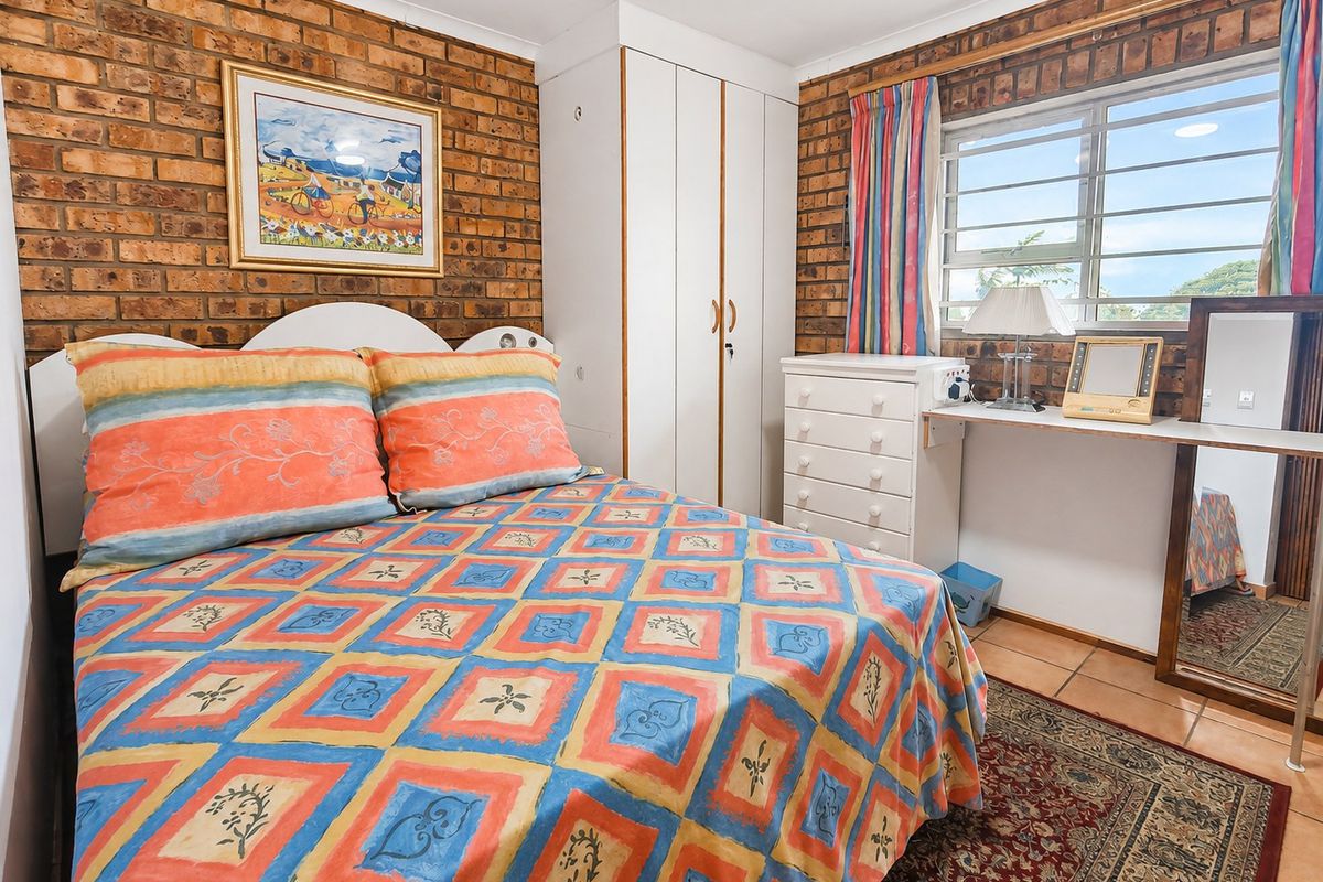 A bedroom featuring exposed brick walls, tiled flooring, and a built-in wardrobe, offering a rustic aesthetic with potential for modern updates.