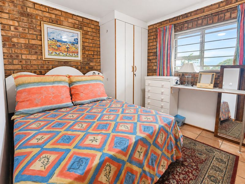 A bedroom featuring exposed brick walls, tiled flooring, and a built-in wardrobe, offering a rustic aesthetic with potential for modern updates.