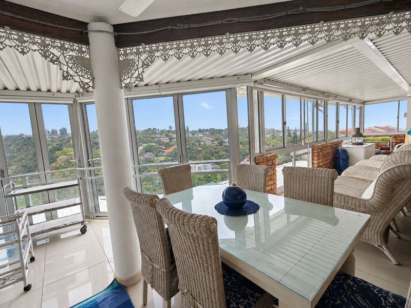 Enclosed balcony featuring tiled flooring, decorative metal detailing, and expansive windows offering panoramic views of the surrounding neighborhood.