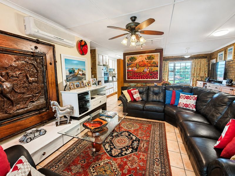 Open-plan living area featuring tiled floors, ceiling fan, air conditioning, and an integrated kitchen with built-in cabinetry and oven.