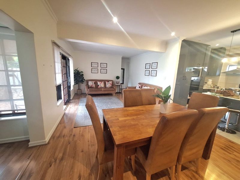 An open-plan living and dining area featuring laminate flooring, recessed lighting, and a seamless transition to the adjacent kitchen space.