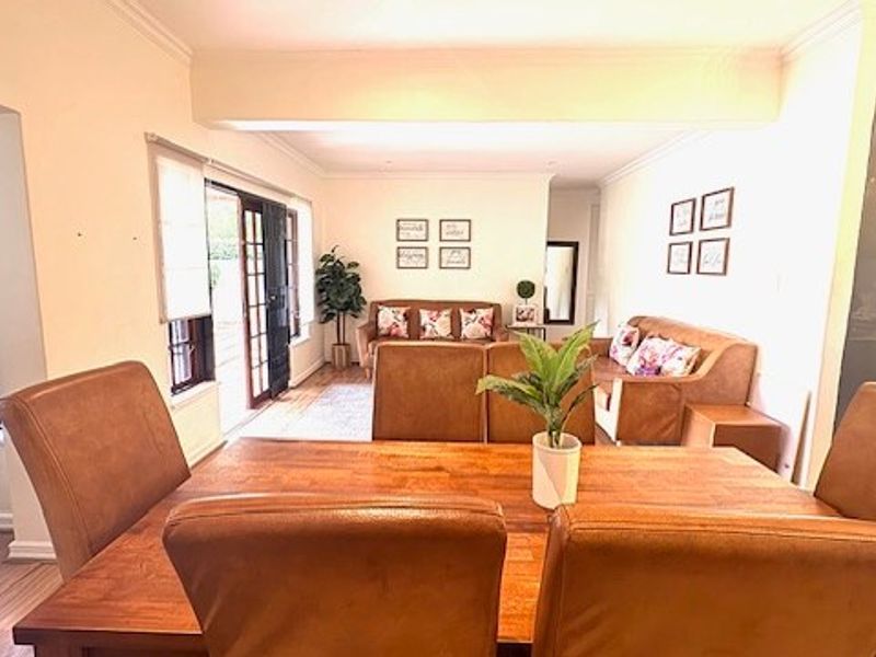 Open plan living and dining area featuring laminate flooring, crown molding, and sliding glass doors leading to the exterior.