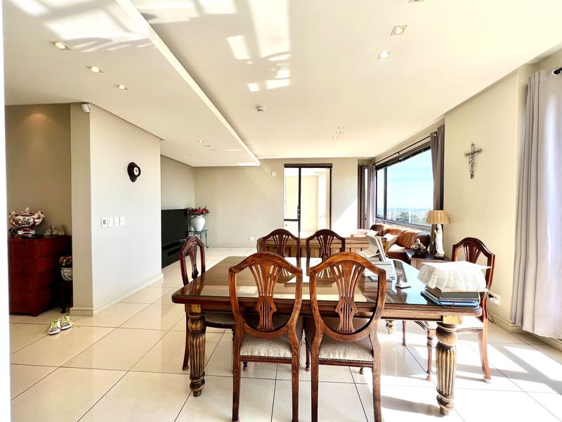 Spacious open-plan living and dining area featuring large windows, recessed ceiling lighting, and neutral tiled flooring throughout.