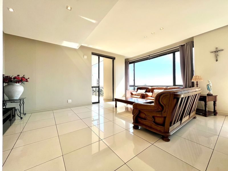 A bright and spacious living room featuring large windows, polished tiled flooring, and direct access to an outdoor balcony area.