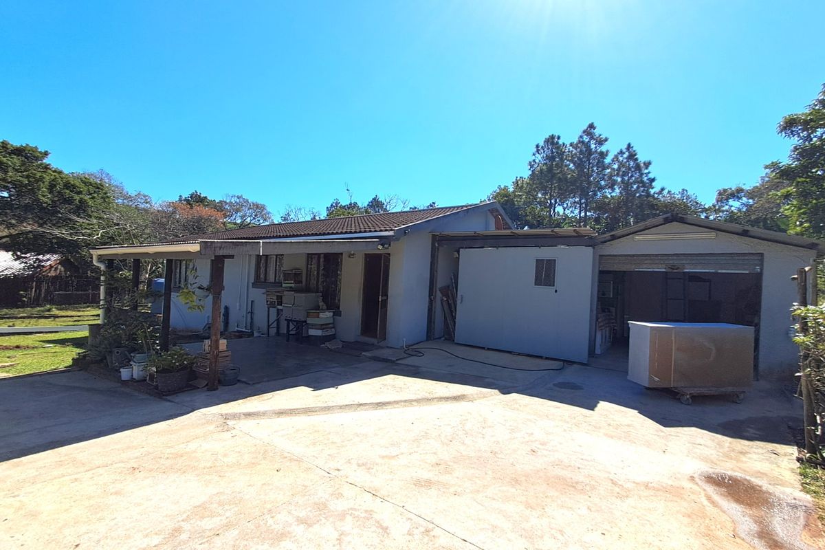 Rear view of the property featuring a concrete driveway, covered patio area, and an attached garage structure.