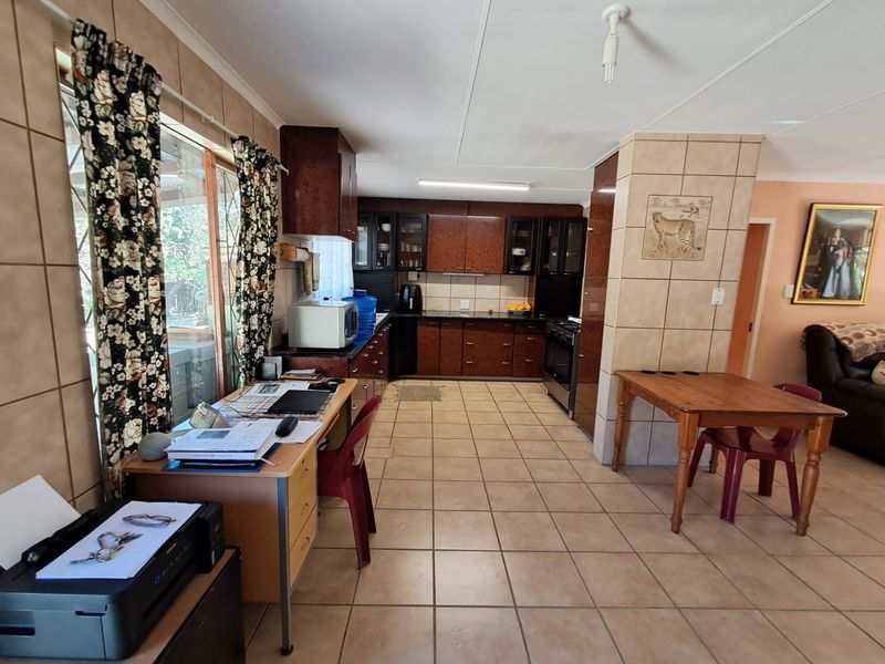 Open plan kitchen and living area featuring tiled flooring, dark wood-look cabinetry, and a tiled feature pillar.