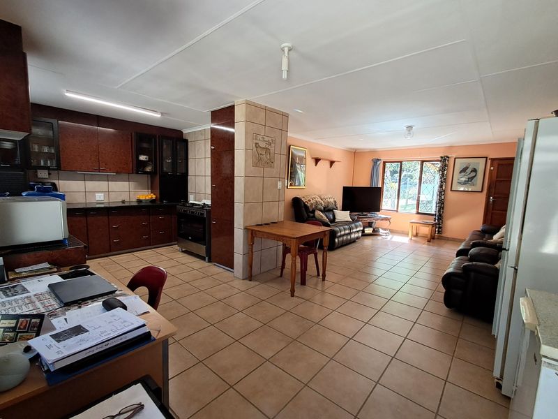 Spacious open-plan living and kitchen area featuring tiled flooring, dark wood-finish cabinetry, and a central tiled pillar.