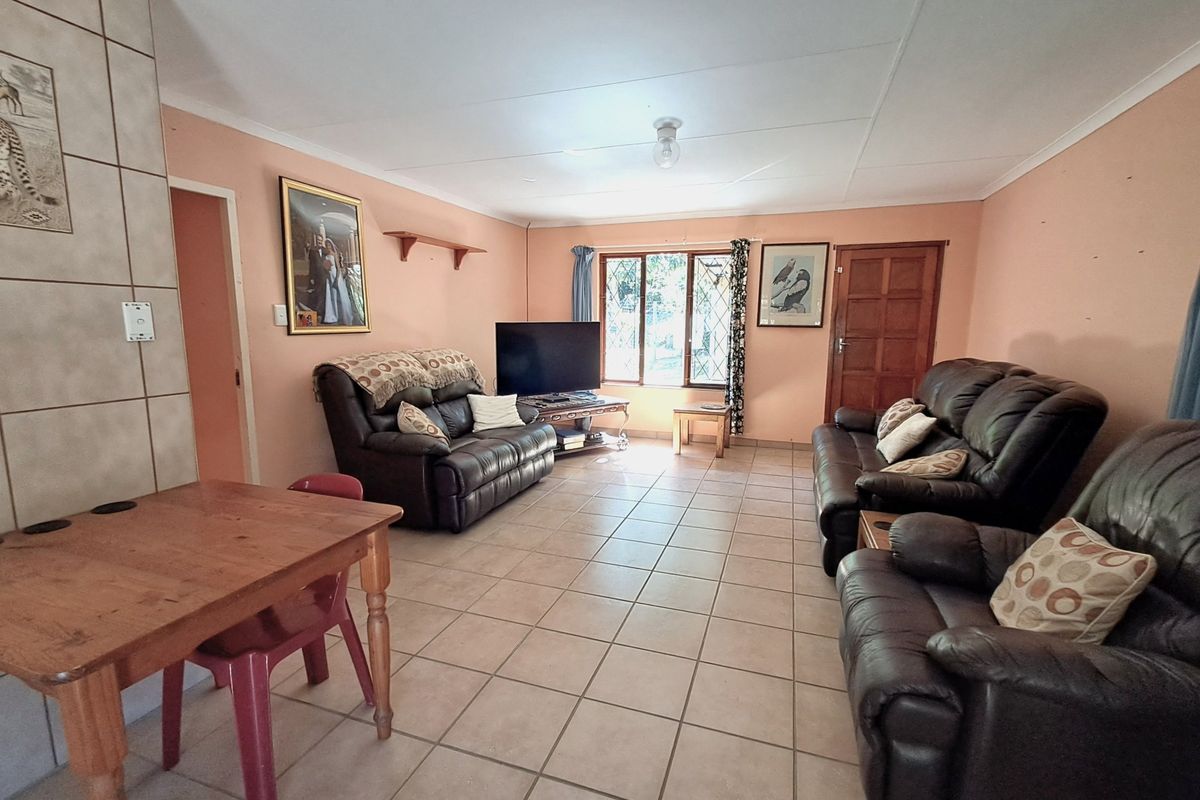 Spacious living room featuring tiled flooring, a tiled fireplace surround, and a timber door, offering a functional layout with natural light.