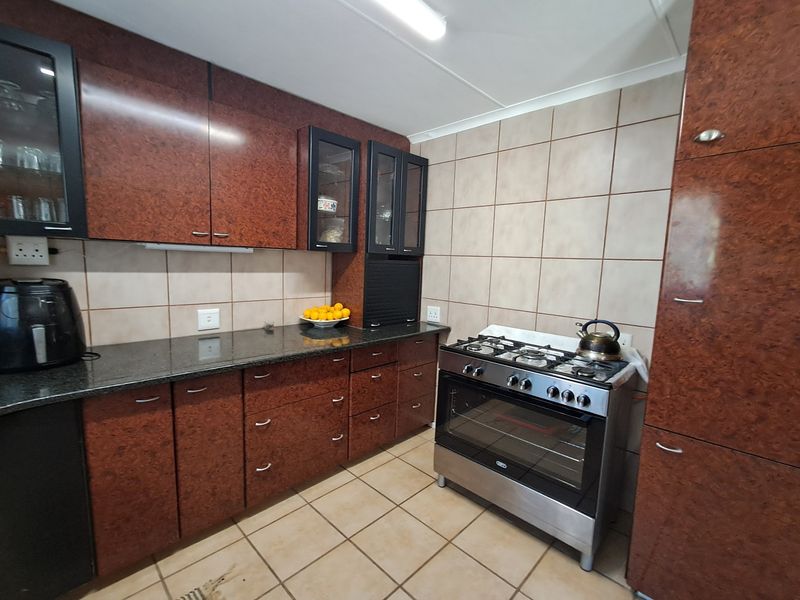A functional kitchen featuring dark laminate cabinetry, granite countertops, tiled backsplash, and a freestanding gas stove with oven.