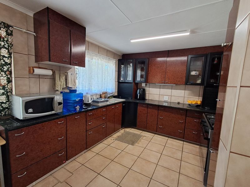 A functional kitchen featuring dark laminate cabinetry, granite countertops, ceramic tiled flooring, and wall tiling throughout.