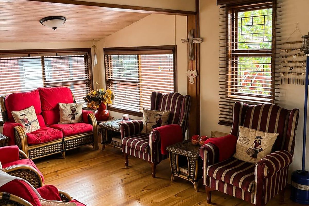 A cozy living room featuring warm timber flooring and a matching timber tongue and groove ceiling, complemented by a decorative stained glass window.