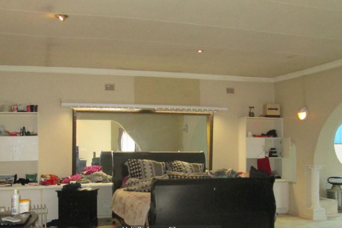 Spacious bedroom featuring built-in shelving, recessed lighting, and a distinctive circular window, with an adjoining arched area.