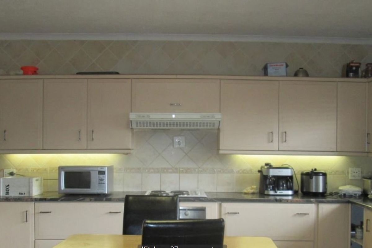 Functional kitchen featuring neutral built-in cabinetry, tiled backsplash, integrated hob and oven, and under-cabinet lighting.