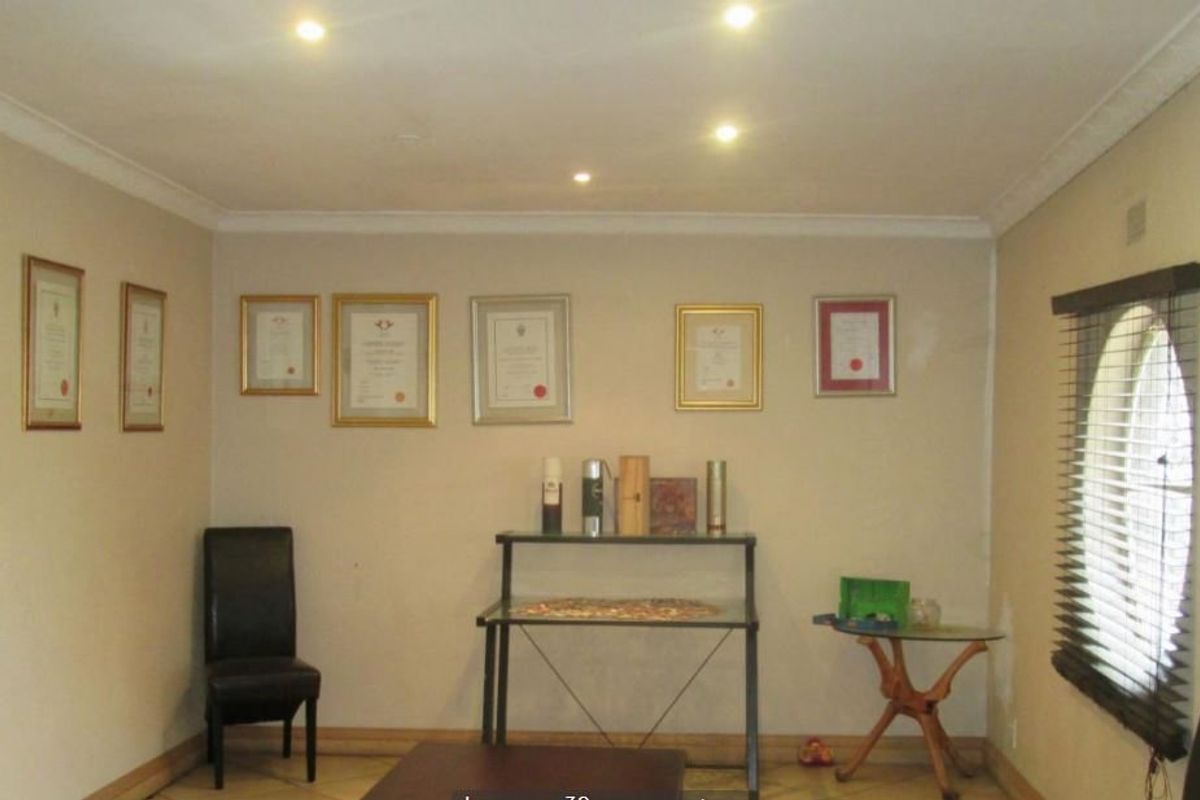 A living room featuring tiled flooring, recessed downlighting, and coved cornicing, with natural light provided by an arched window.
