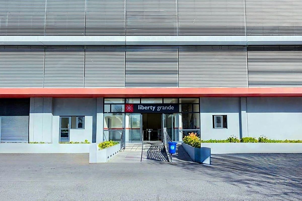 The front entrance of Liberty Grande apartment complex, featuring a modern facade with louvre cladding and a glass-paneled doorway.