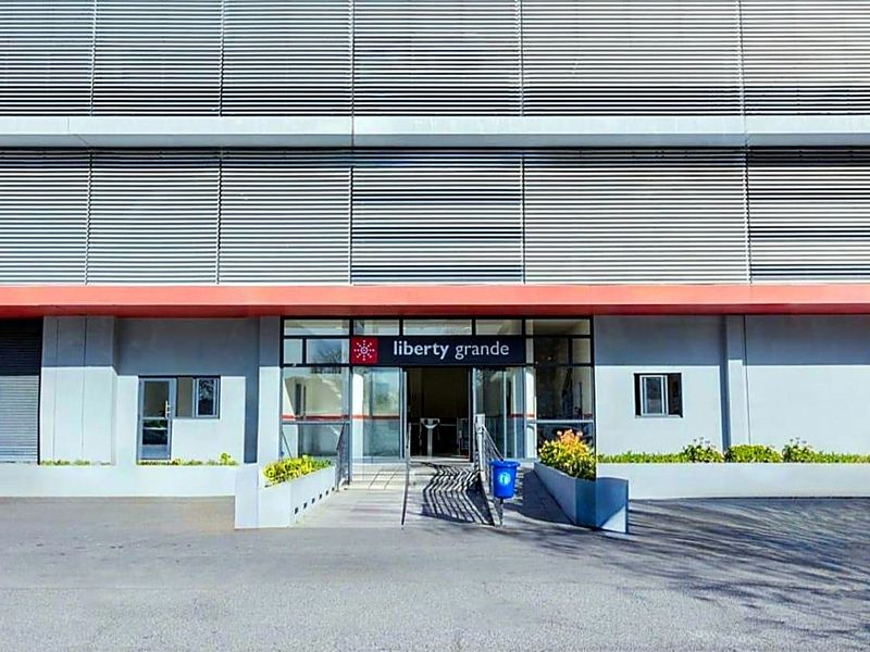 The front entrance of Liberty Grande apartment complex, featuring a modern facade with louvre cladding and a glass-paneled doorway.