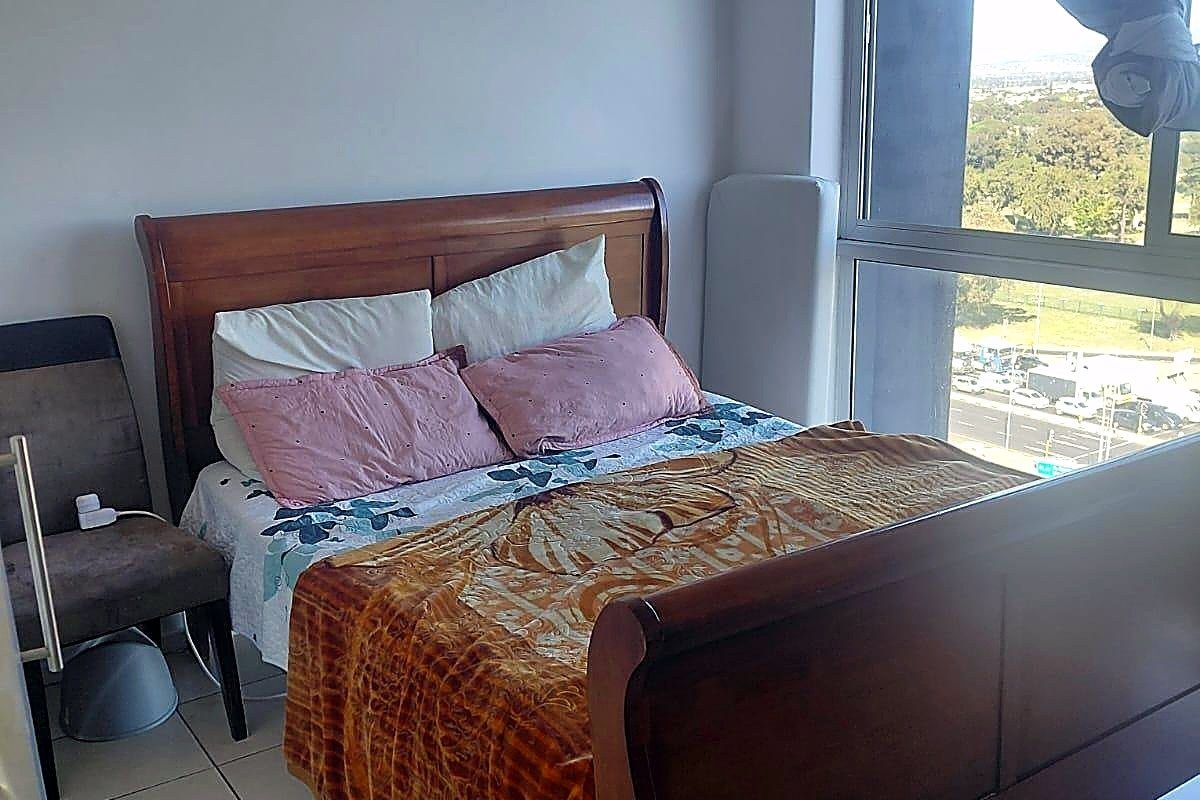 A bedroom featuring tiled flooring and a large window providing natural light and an elevated view.