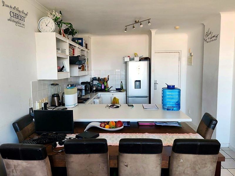 Open plan kitchen and dining area featuring a breakfast bar, tiled flooring, and functional cabinetry, providing a versatile space for cooking and casual dining.