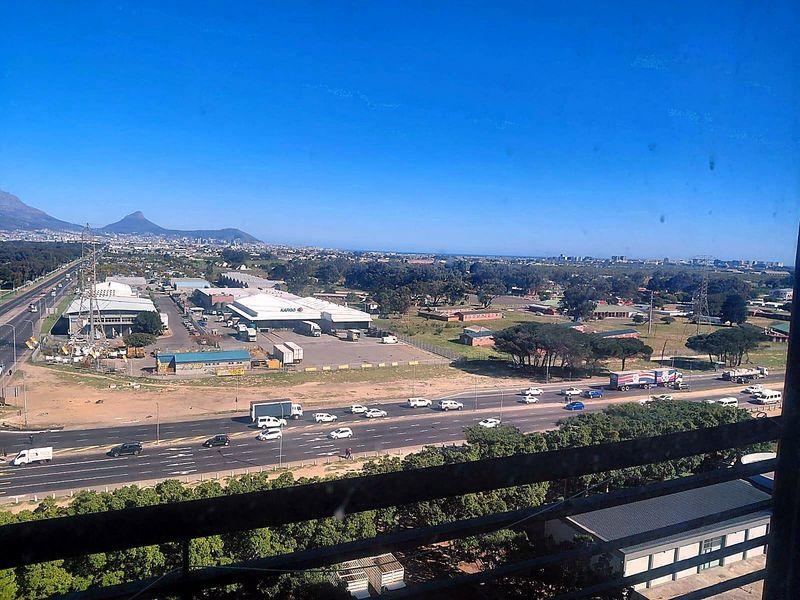 Elevated panoramic view overlooking the surrounding landscape, industrial area, and major road infrastructure from an apartment balcony.