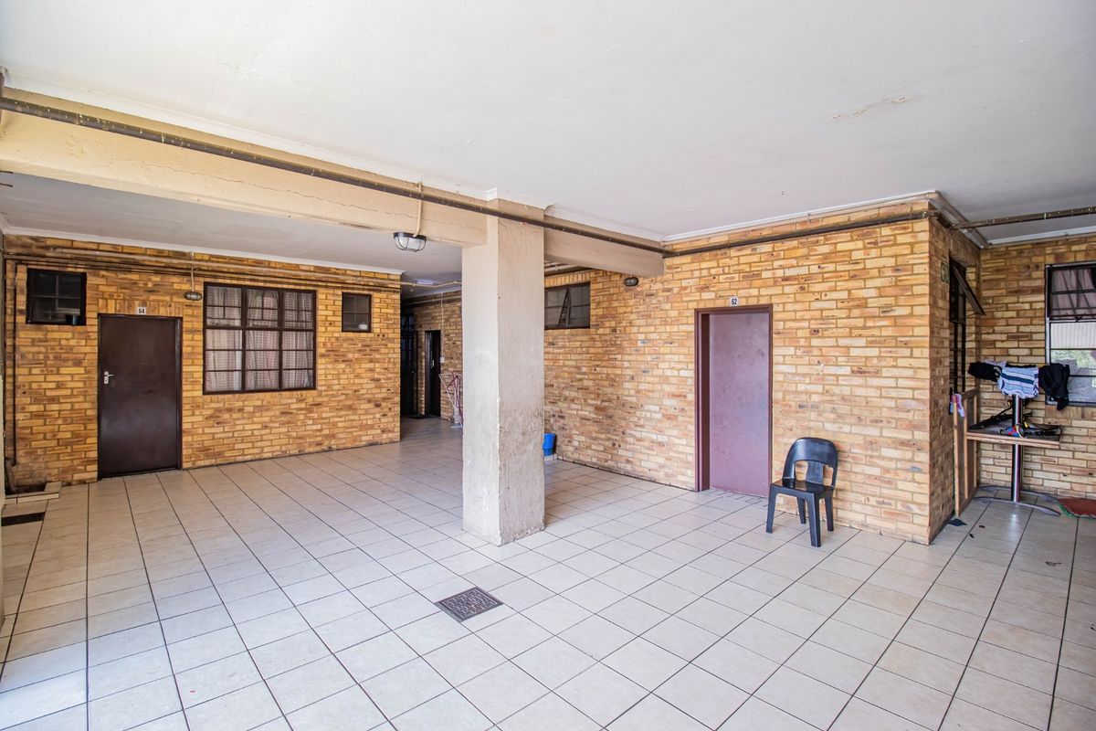 A covered outdoor communal area featuring exposed brick walls, tiled flooring, and a central concrete support pillar.