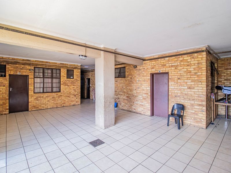 A covered outdoor communal area featuring exposed brick walls, tiled flooring, and a central concrete support pillar.