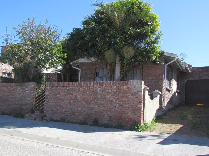 Front exterior view of a face brick house featuring a perimeter boundary wall, metal pedestrian gate, and attached garage.