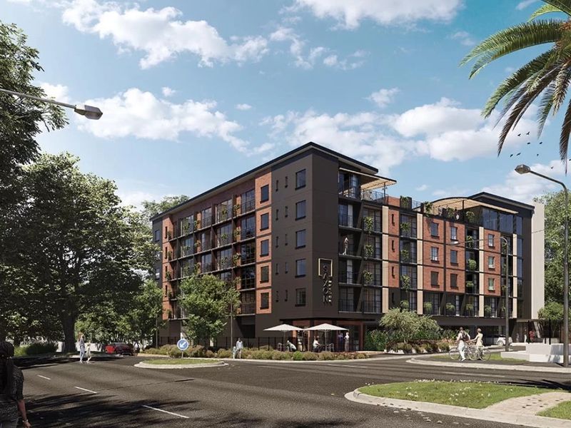 A modern multi-story apartment building featuring a brick and dark metal facade with integrated balconies, situated on a corner lot.