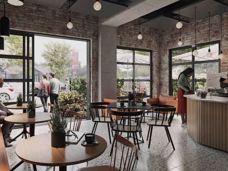 Modern open-plan commercial space featuring exposed brick walls, terrazzo flooring, and large industrial-style windows with ample natural light.