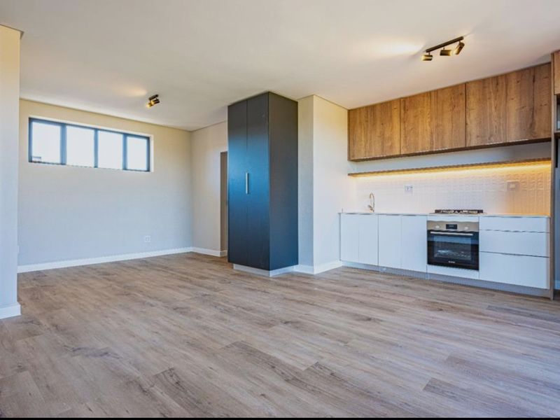Modern open-plan living area featuring a sleek kitchen with built-in cabinetry, integrated oven, gas hob, and durable laminate flooring throughout.