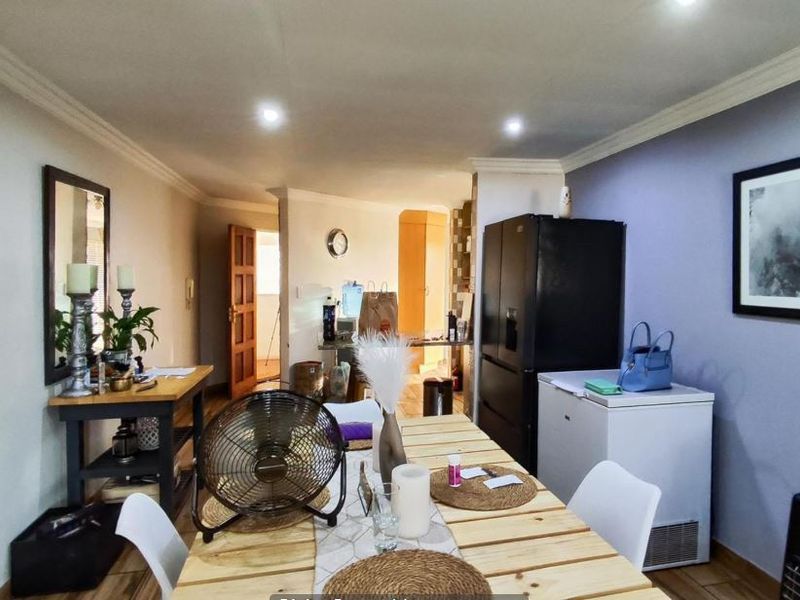Open-plan living and dining area featuring tiled flooring, recessed downlighting, and decorative cornicing, providing a versatile space for daily living.