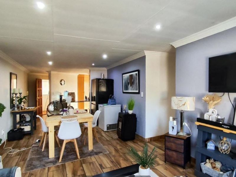 Open-plan living and dining area featuring laminate flooring and recessed downlighting, creating a functional and connected space.
