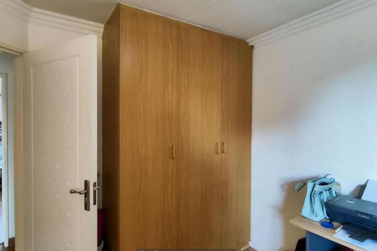 A bedroom featuring a large, wood-finish built-in wardrobe and decorative ceiling coving, providing ample storage space.