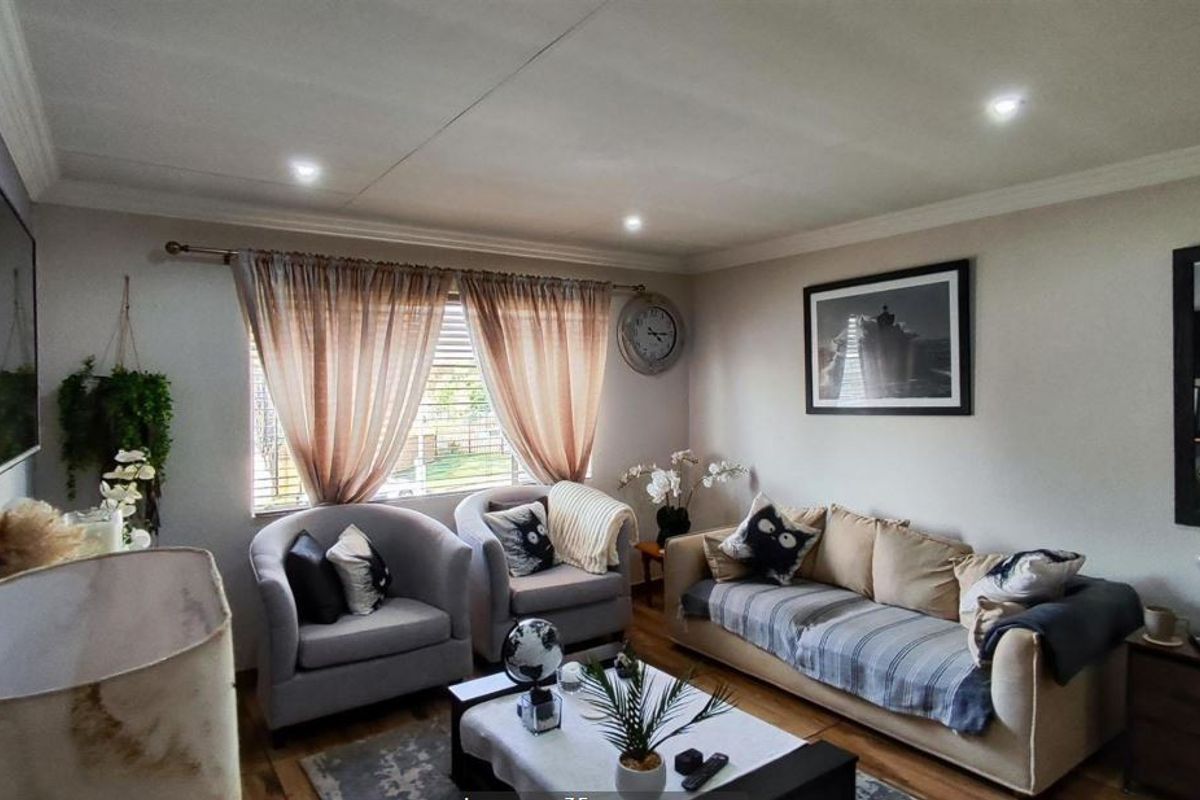 A comfortable living room featuring laminate flooring, recessed downlighting, and decorative cornicing, creating a warm and inviting atmosphere.